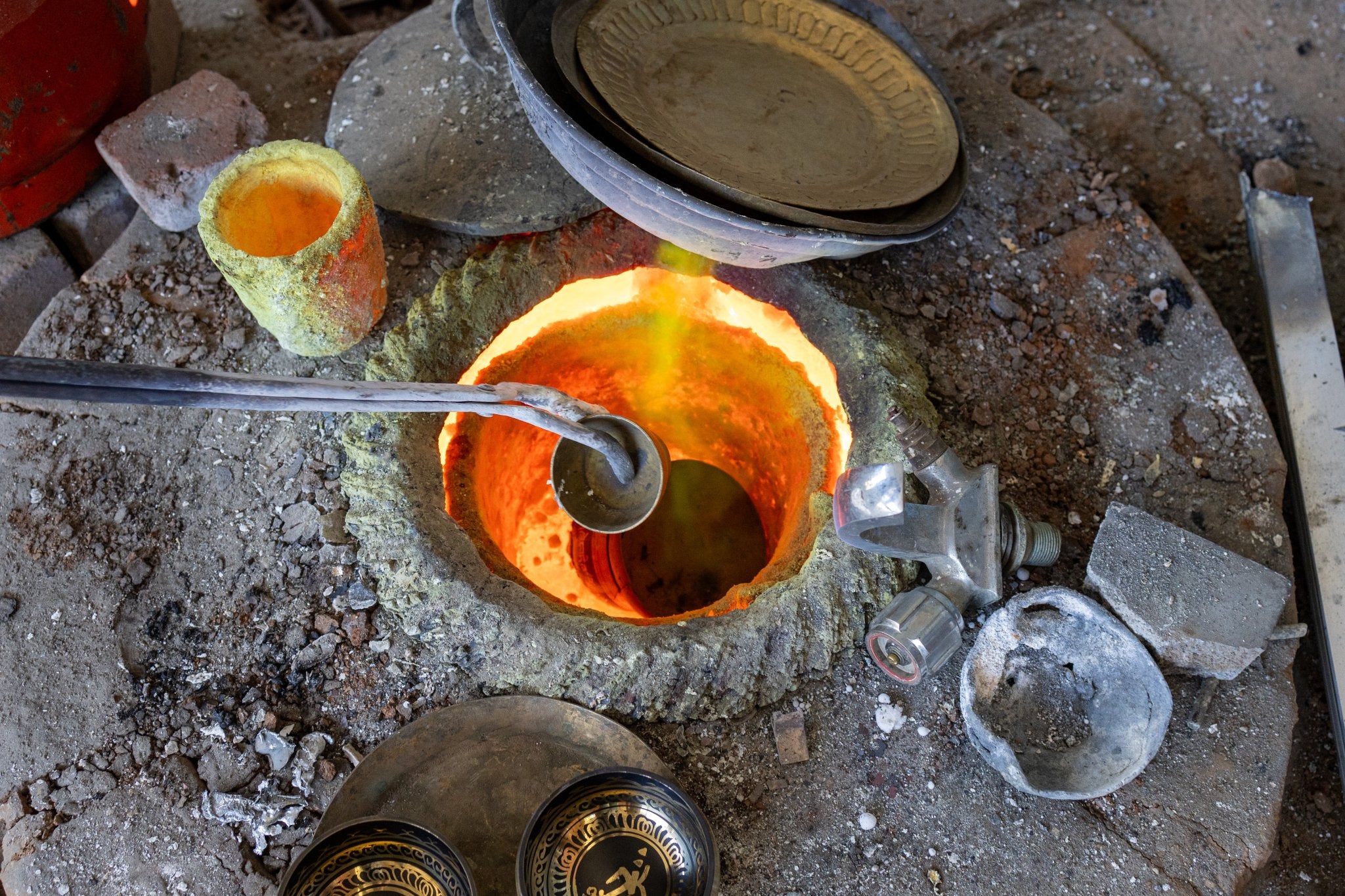A traditional forge in Nepal, molten metal being poured to cast a singing bowl