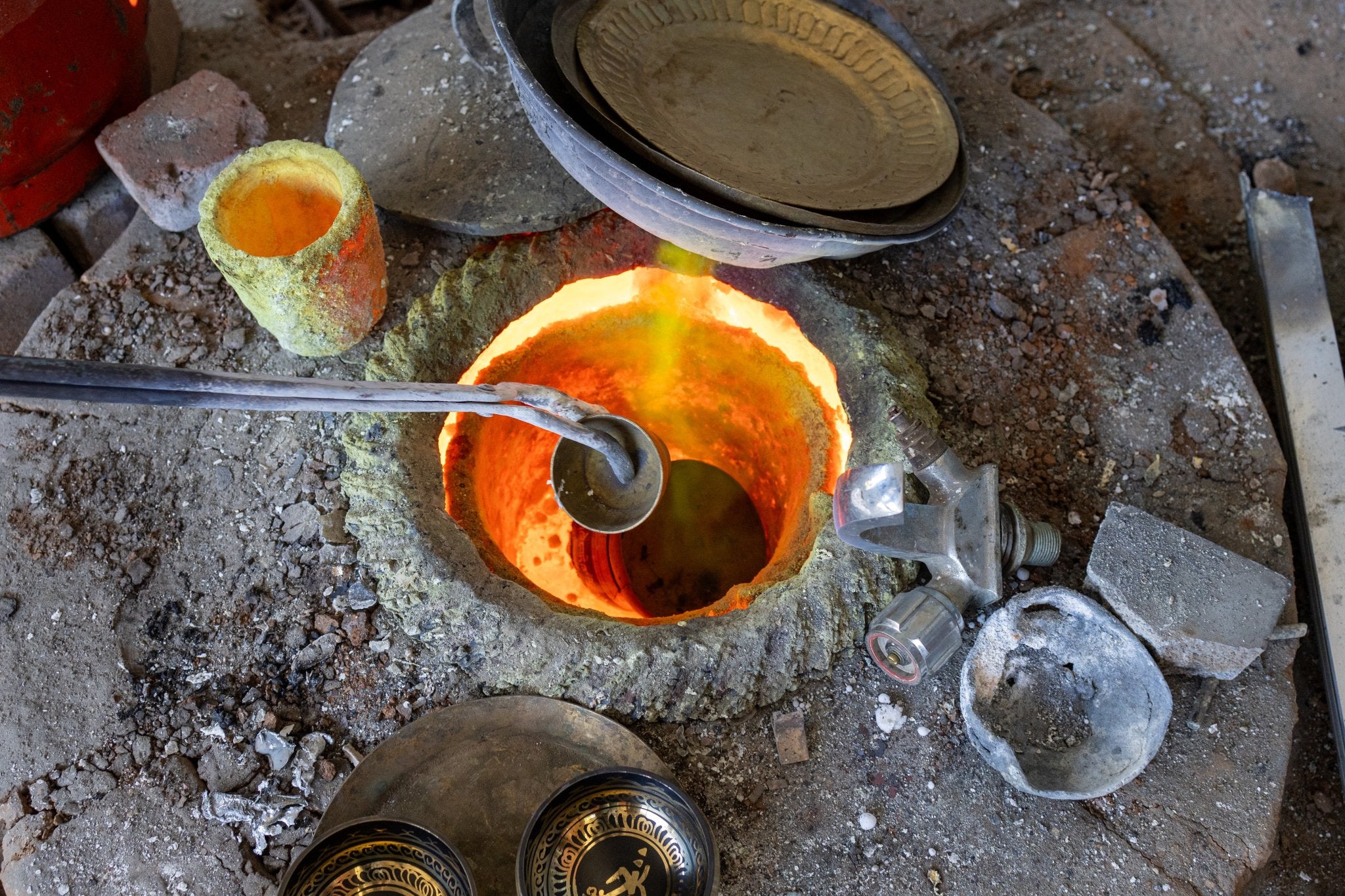 artisan heating a singing bowl over furnace